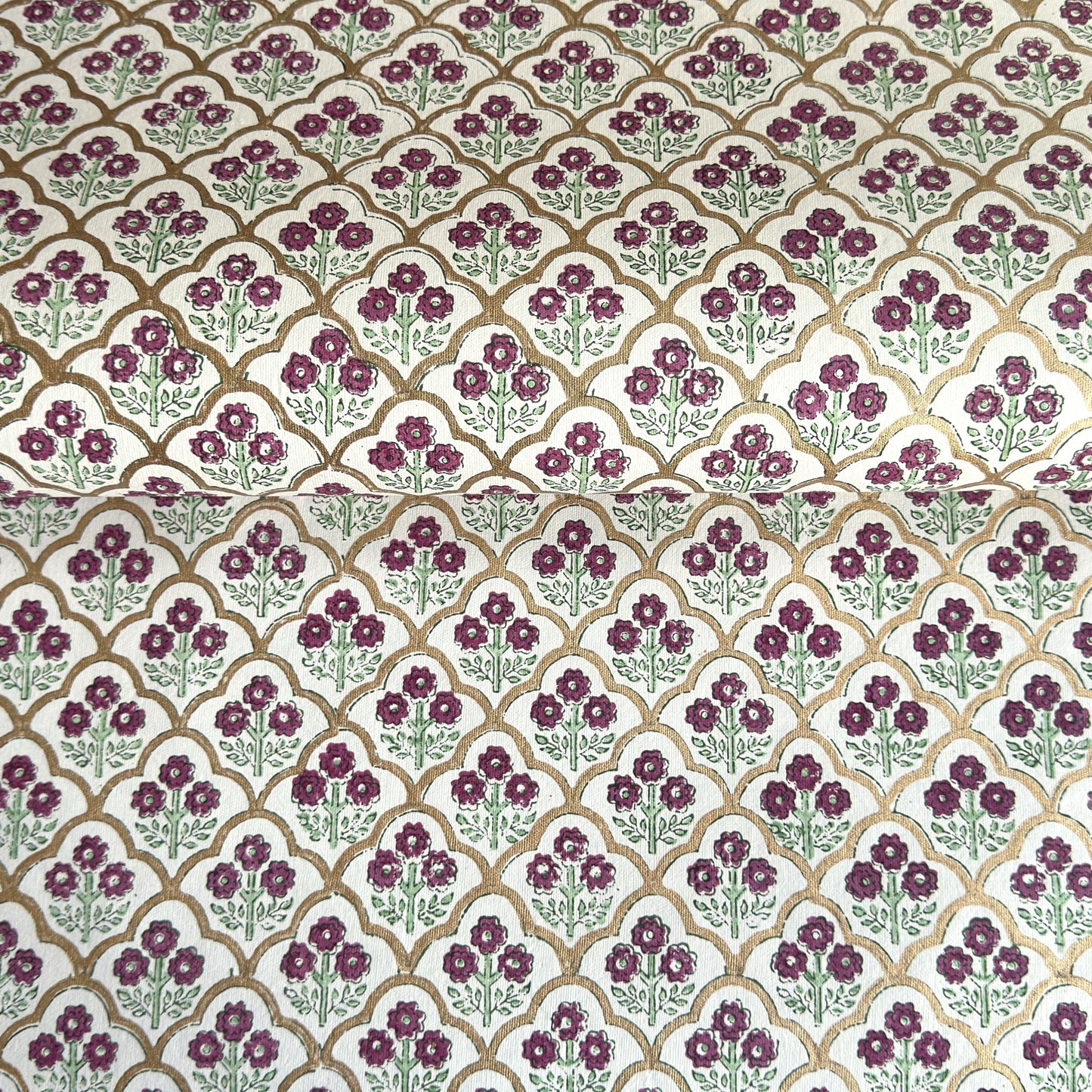 Hand block printed wrapping paper with a trellis pattern with flowers in cherry red, green and gold.