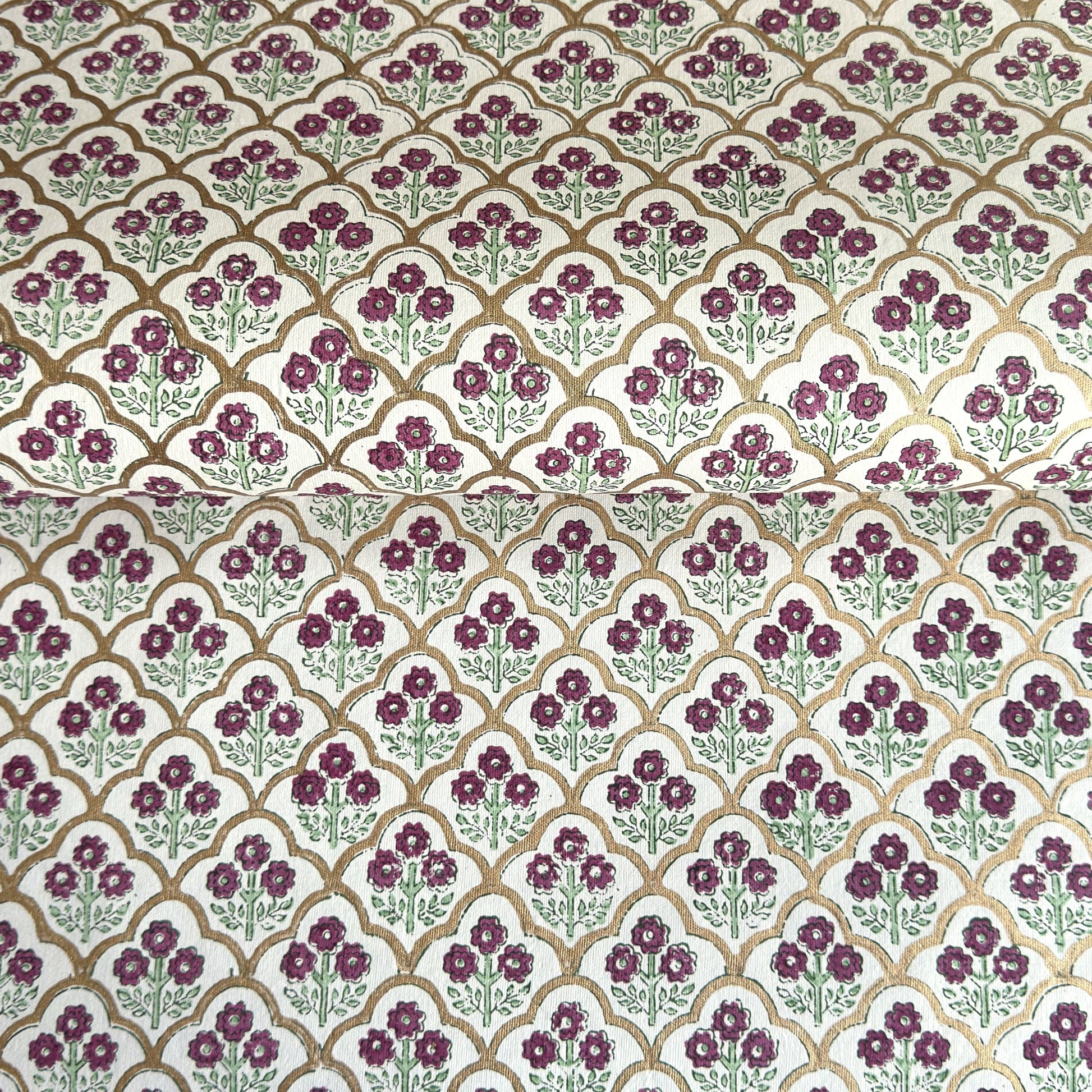 Hand block printed wrapping paper with a trellis pattern with flowers in cherry red, green and gold.