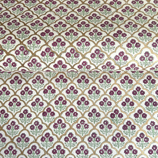 Hand block printed wrapping paper with a trellis pattern with flowers in cherry red, green and gold.