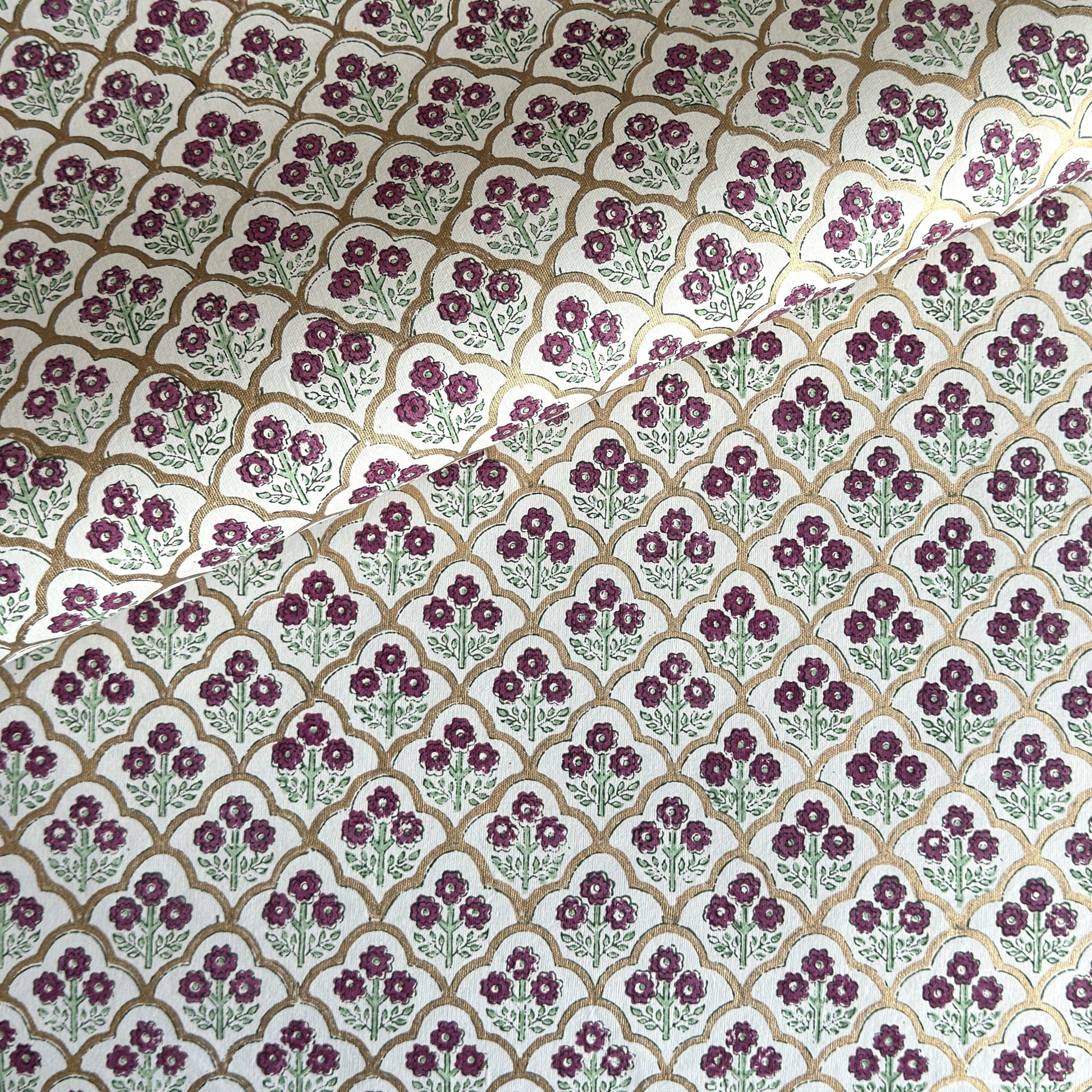 Hand block printed wrapping paper with a trellis pattern with flowers in cherry red, green and gold.
