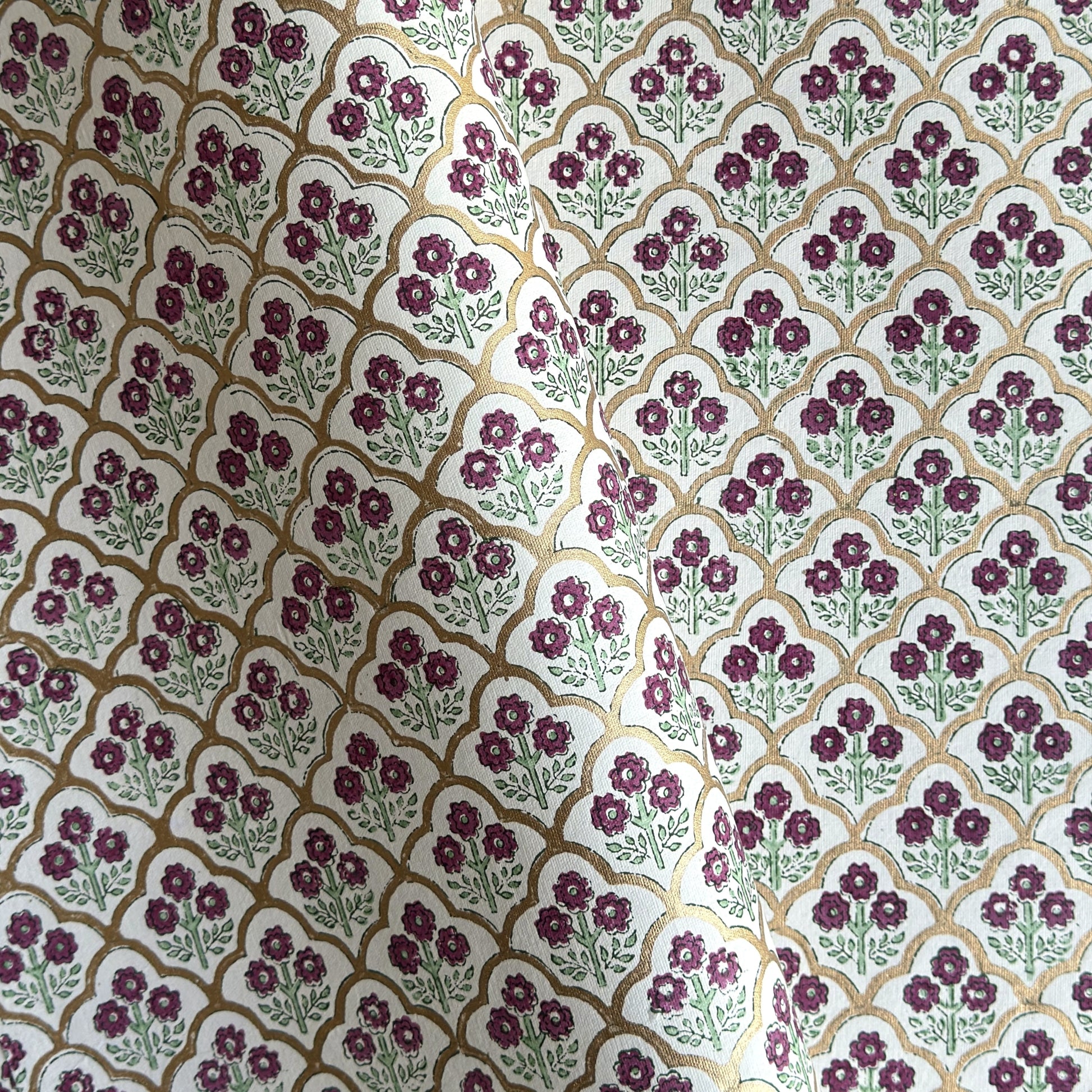 Hand block printed wrapping paper with a trellis pattern with flowers in cherry red, green and gold.