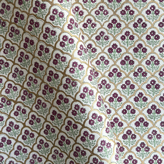 Hand block printed wrapping paper with a trellis pattern with flowers in cherry red, green and gold.