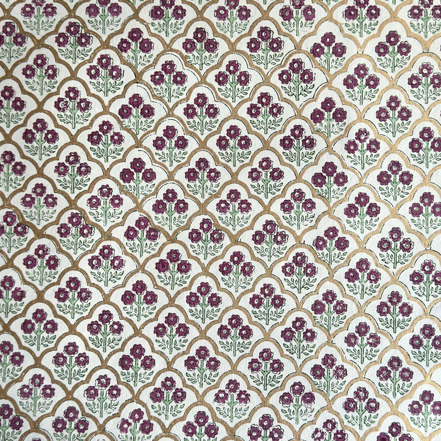 Hand block printed wrapping paper with a trellis pattern with flowers in cherry red, green and gold.