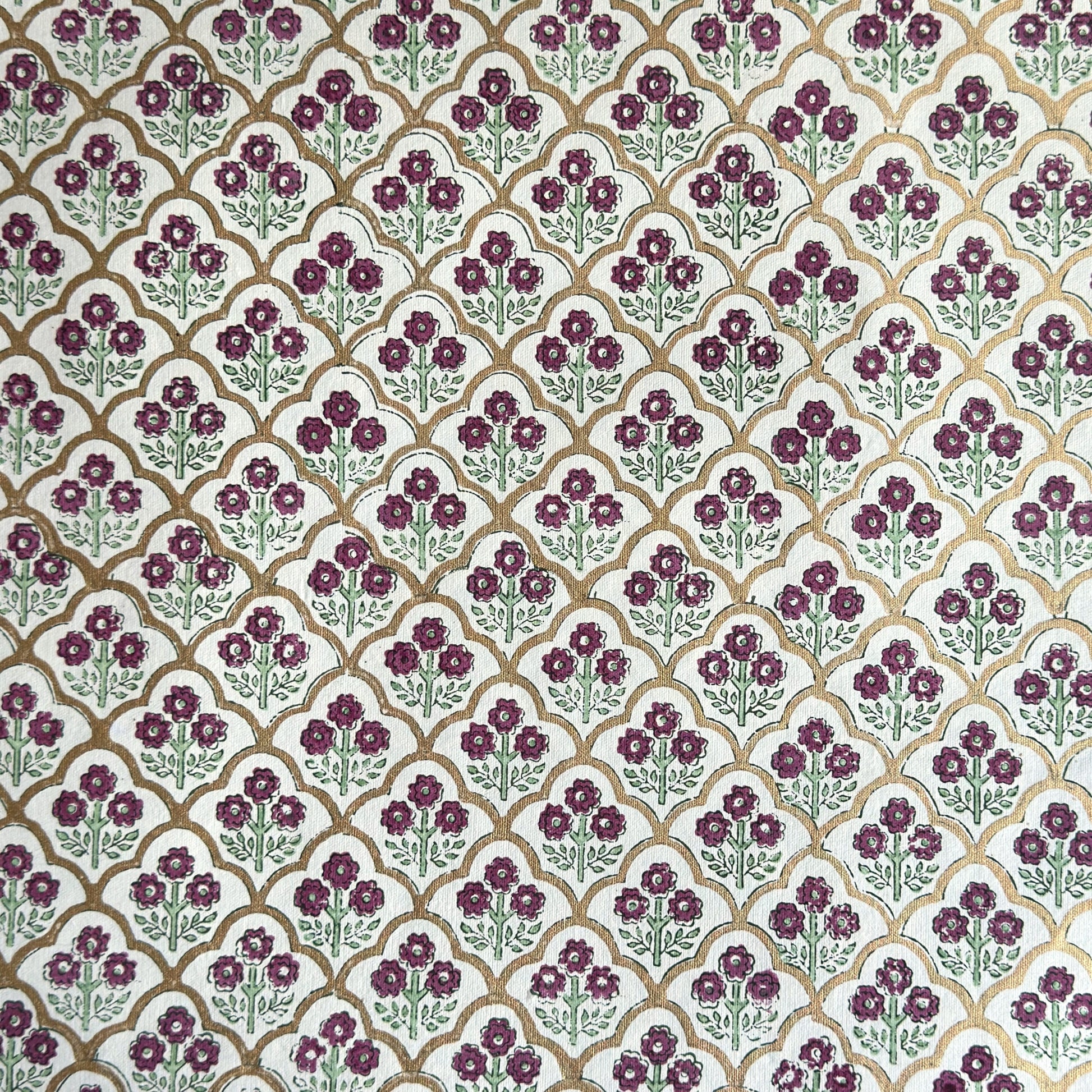 Hand block printed wrapping paper with a trellis pattern with flowers in cherry red, green and gold.