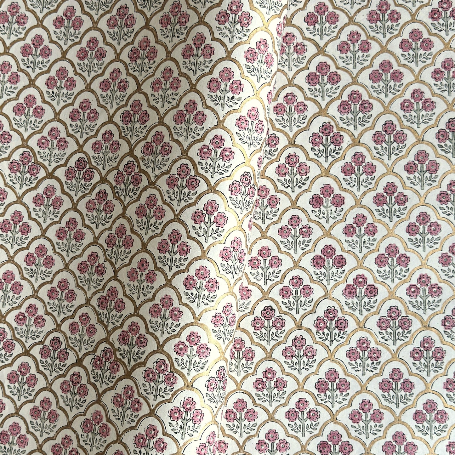 hand block printed wrapping paper by Paper Mirchi.  Repeat pattern of little flowers in pink and green within a gold trellis design.
