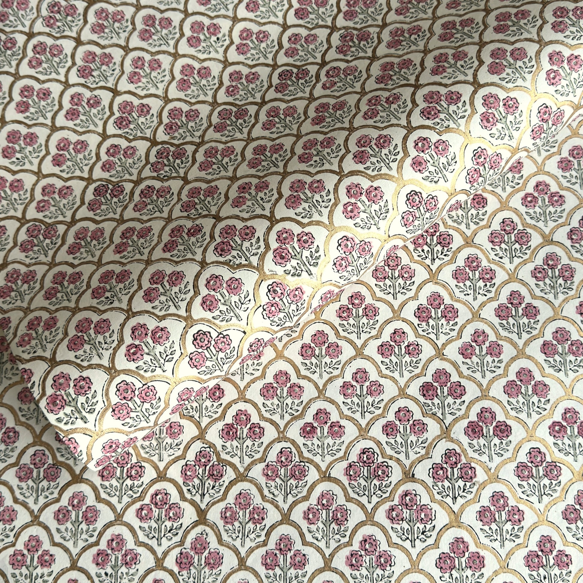 hand block printed wrapping paper by Paper Mirchi.  Repeat pattern of little flowers in pink and green within a gold trellis design.
