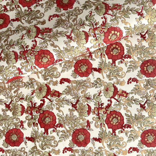 a sheet of hand block printed wrapping paper with a wild rose repeat design in scarlet red with soft green leaves and gold accents