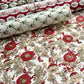a sheet of hand block printed wrapping paper with a wild rose repeat design in scarlet red with soft green leaves and gold accents