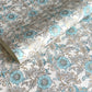 a sheet of hand block printed wrapping paper with a floral wild rose design in opal blue and gold