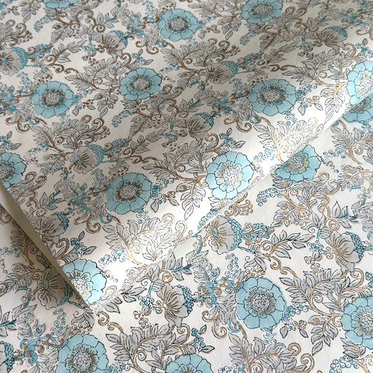 a sheet of hand block printed wrapping paper with a floral wild rose design in opal blue and gold
