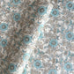 a sheet of hand block printed wrapping paper with a floral wild rose design in opal blue and gold