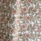 a hand block printed sheet of wrapping paper with a wild rose design in coral, moss green on a white background