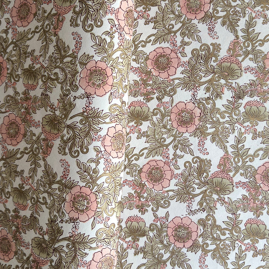 a hand block printed sheet of wrapping paper with a wild rose design in coral, moss green on a white background