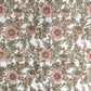 a hand block printed sheet of wrapping paper with a wild rose design in coral, moss green on a white background