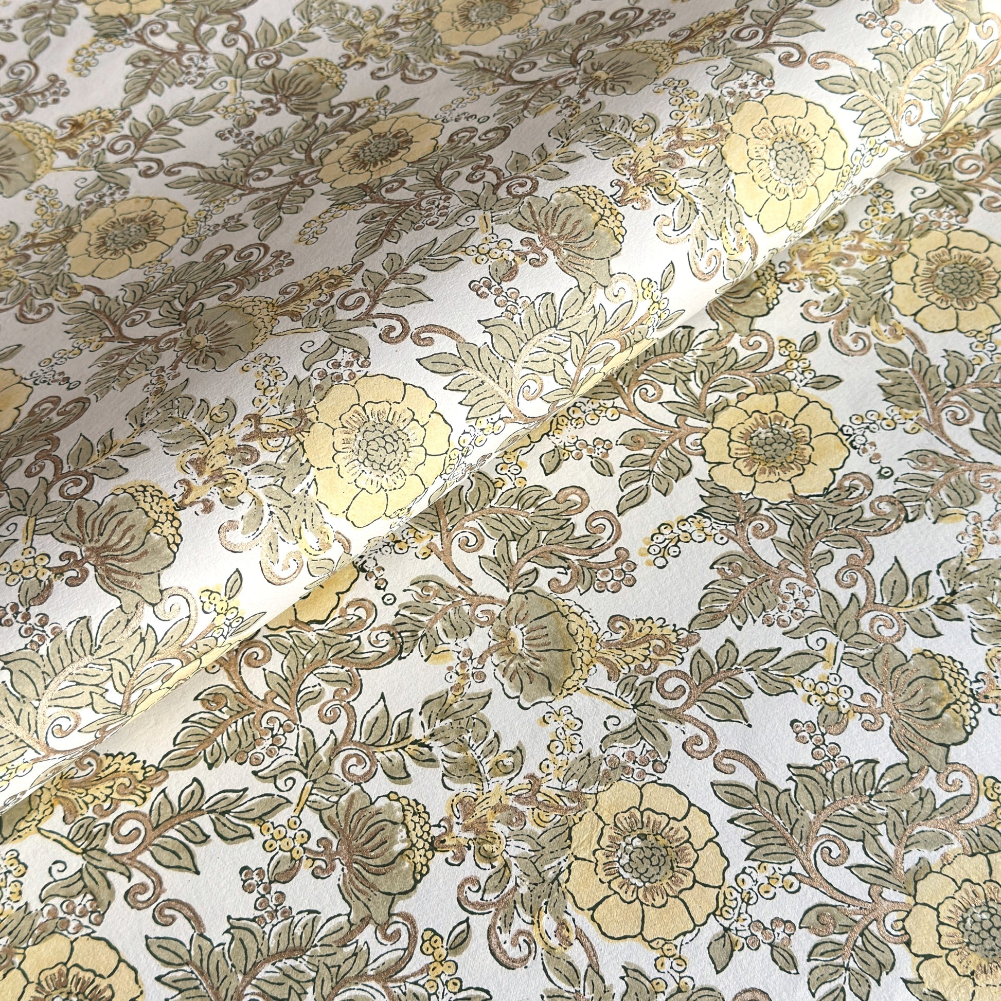 a sheet of hand block printed wrapping paper with a wild rose pattern in buttermilk yellow, moss green and gold