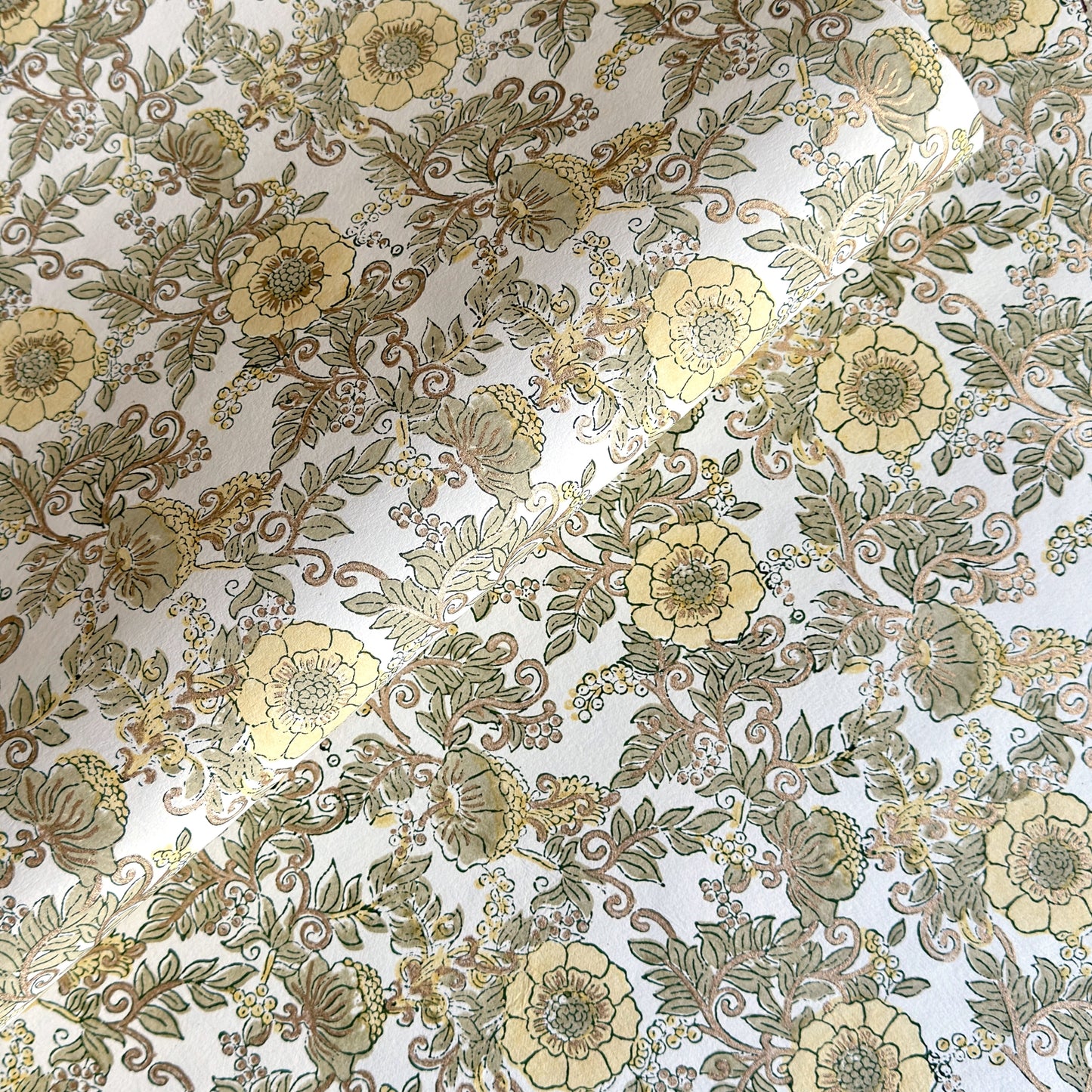a sheet of hand block printed wrapping paper with a wild rose pattern in buttermilk yellow, moss green and gold