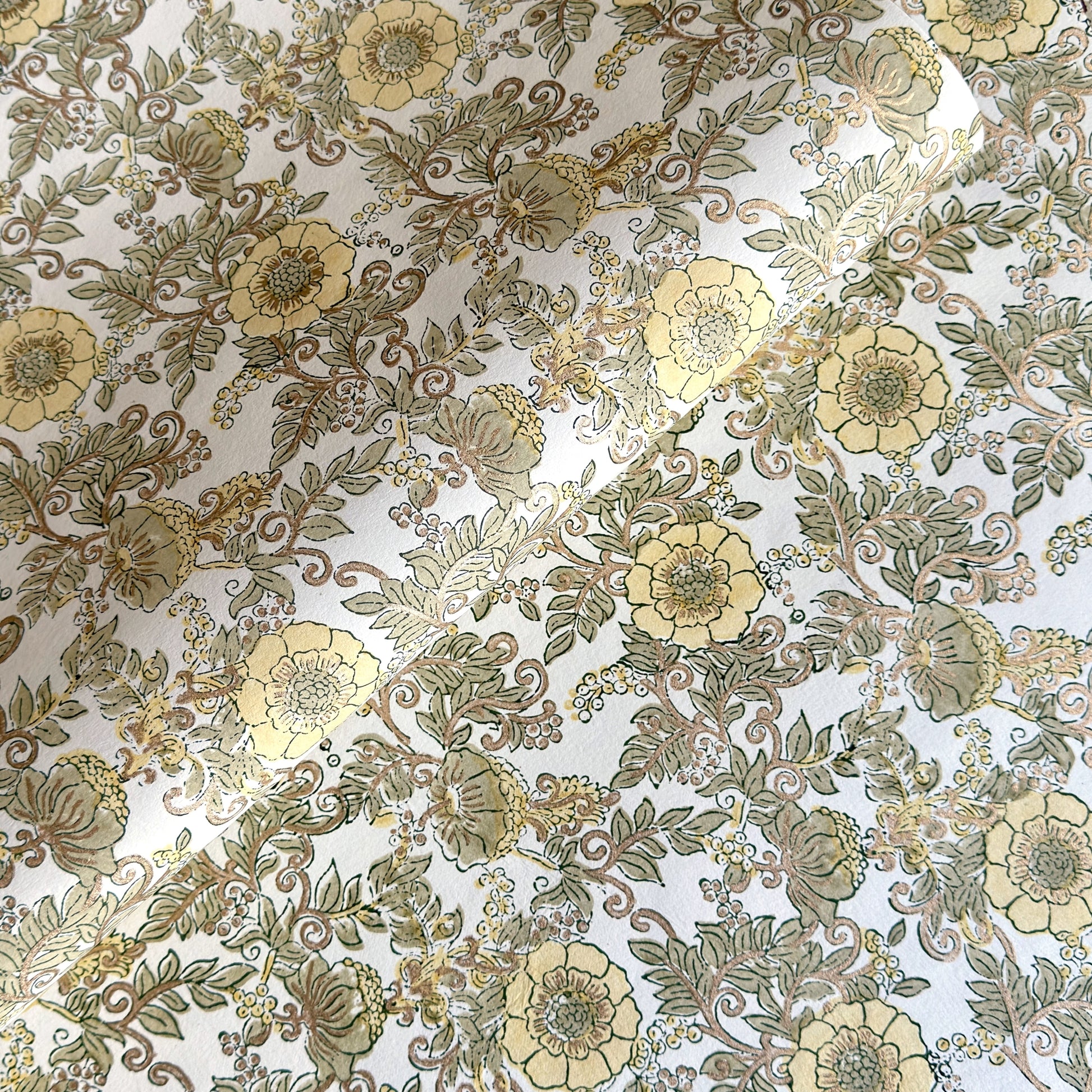 a sheet of hand block printed wrapping paper with a wild rose pattern in buttermilk yellow, moss green and gold