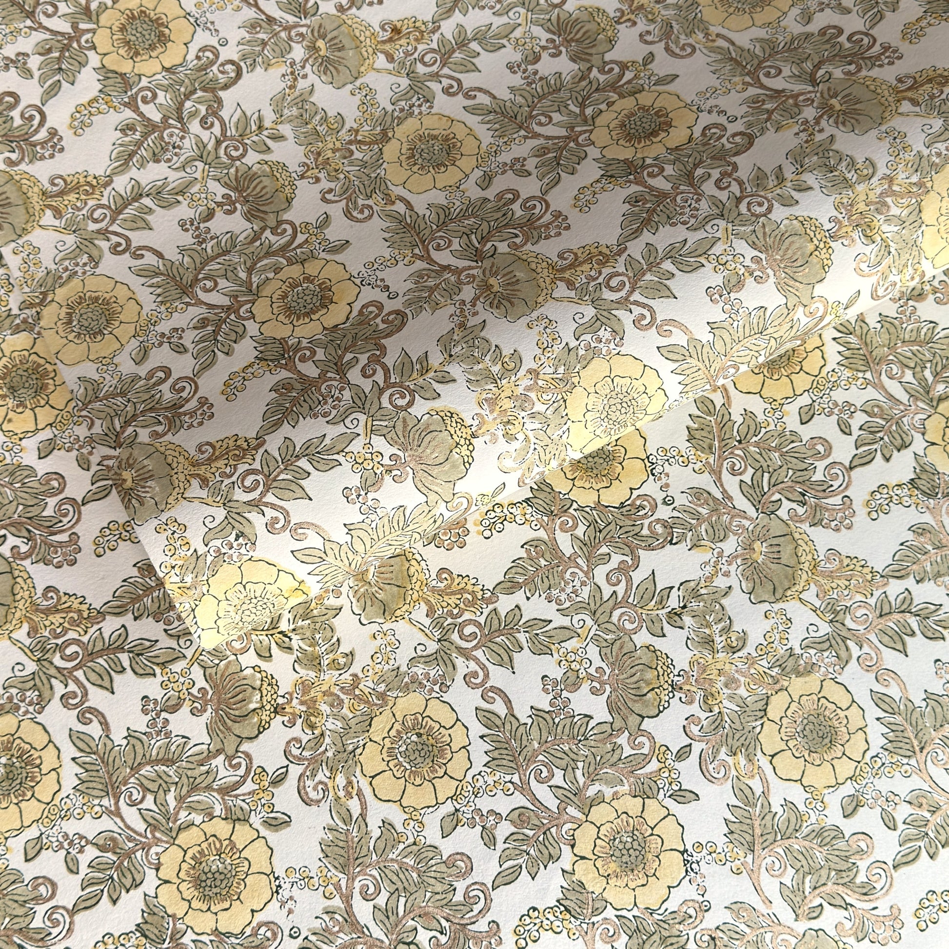 a sheet of hand block printed wrapping paper with a wild rose pattern in buttermilk yellow, moss green and gold