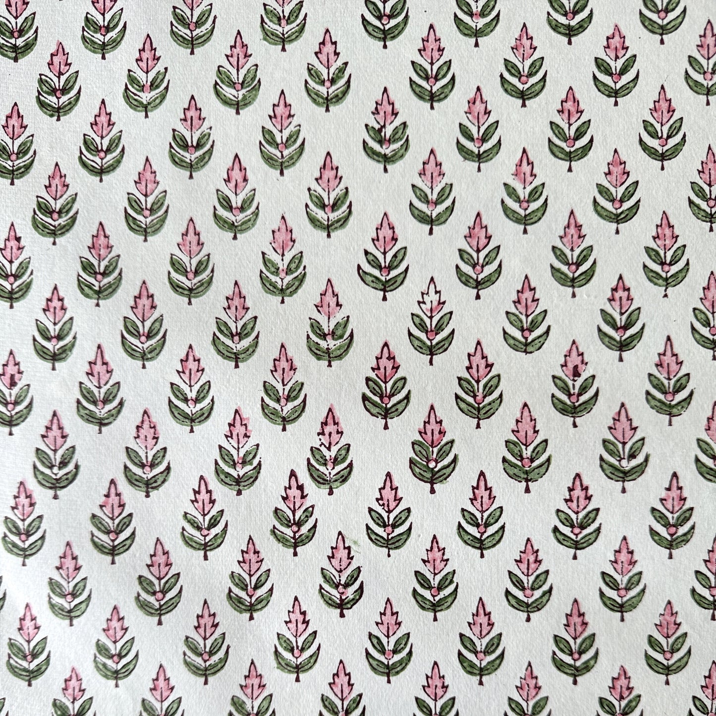 hand block printed paper by Paper Mirchi.  Repeat design of a stylised flower in blush pink and green on a white background.