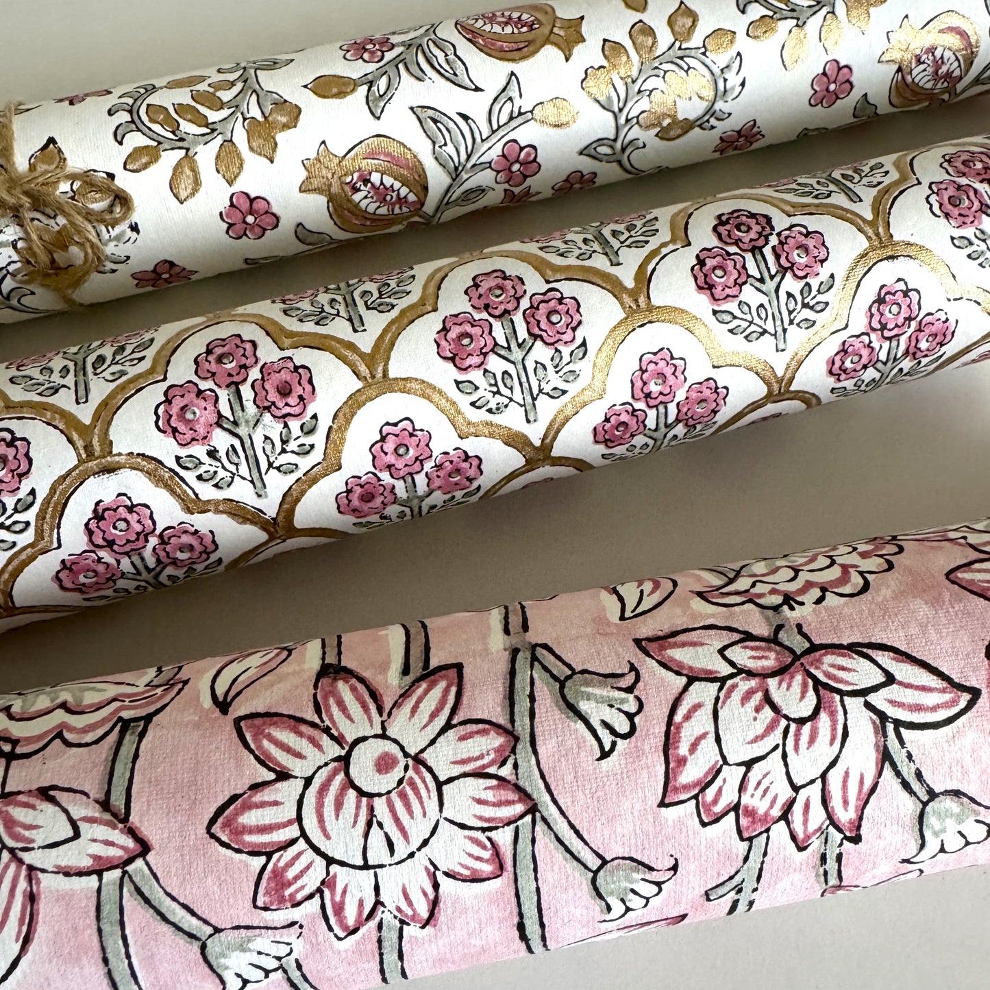 hand block printed wrapping paper by Paper Mirchi. Lotus flower repeat pattern in pale pink, close-up rolled