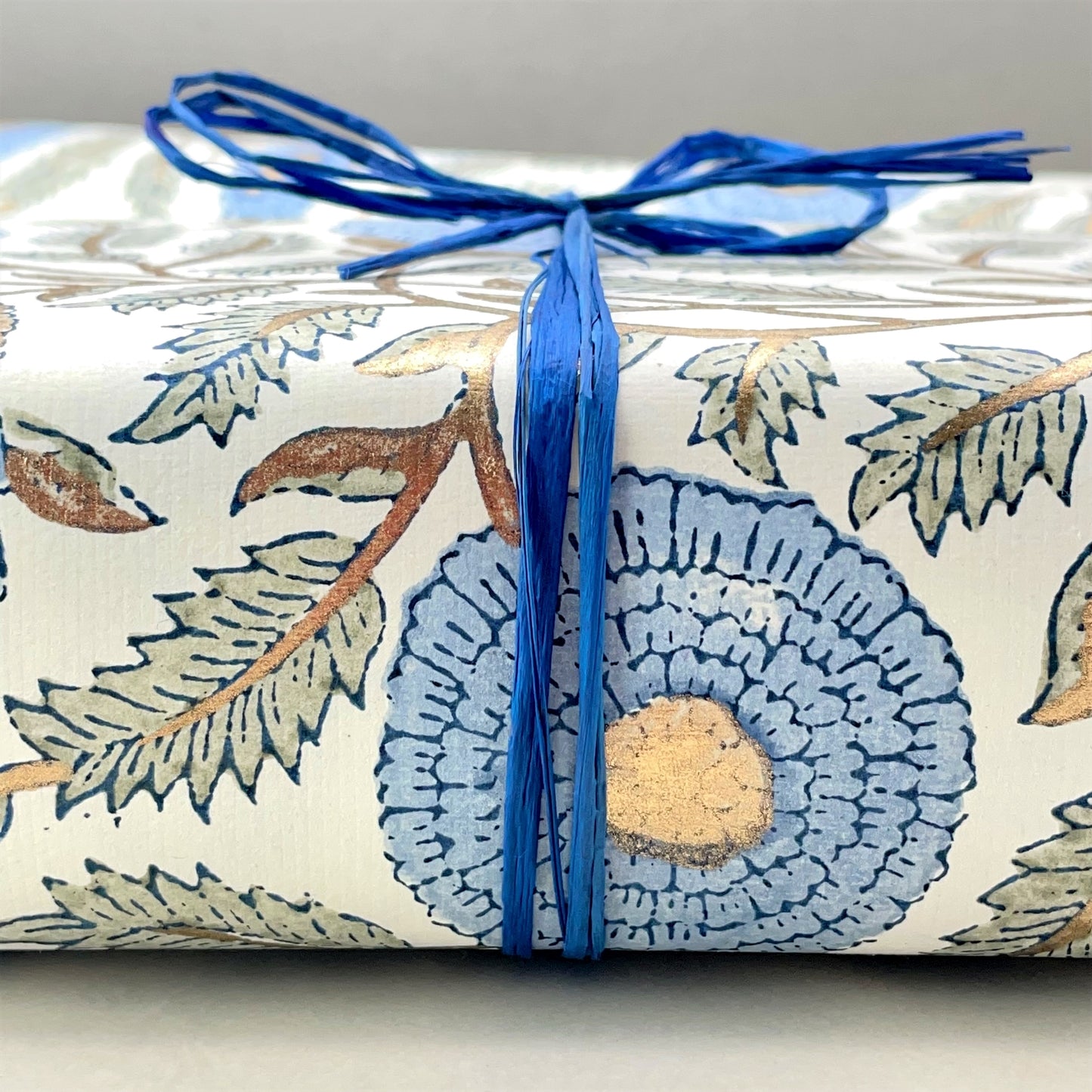 wrapping paper with repeat botanical pattern in blue, gold and green, close-up