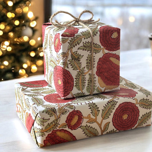 hand block printed paper by Paper Mirchi.  A floral repeat pattern in deep burgundy, pale green and gold. Pictured wrapping two presents and tied with string