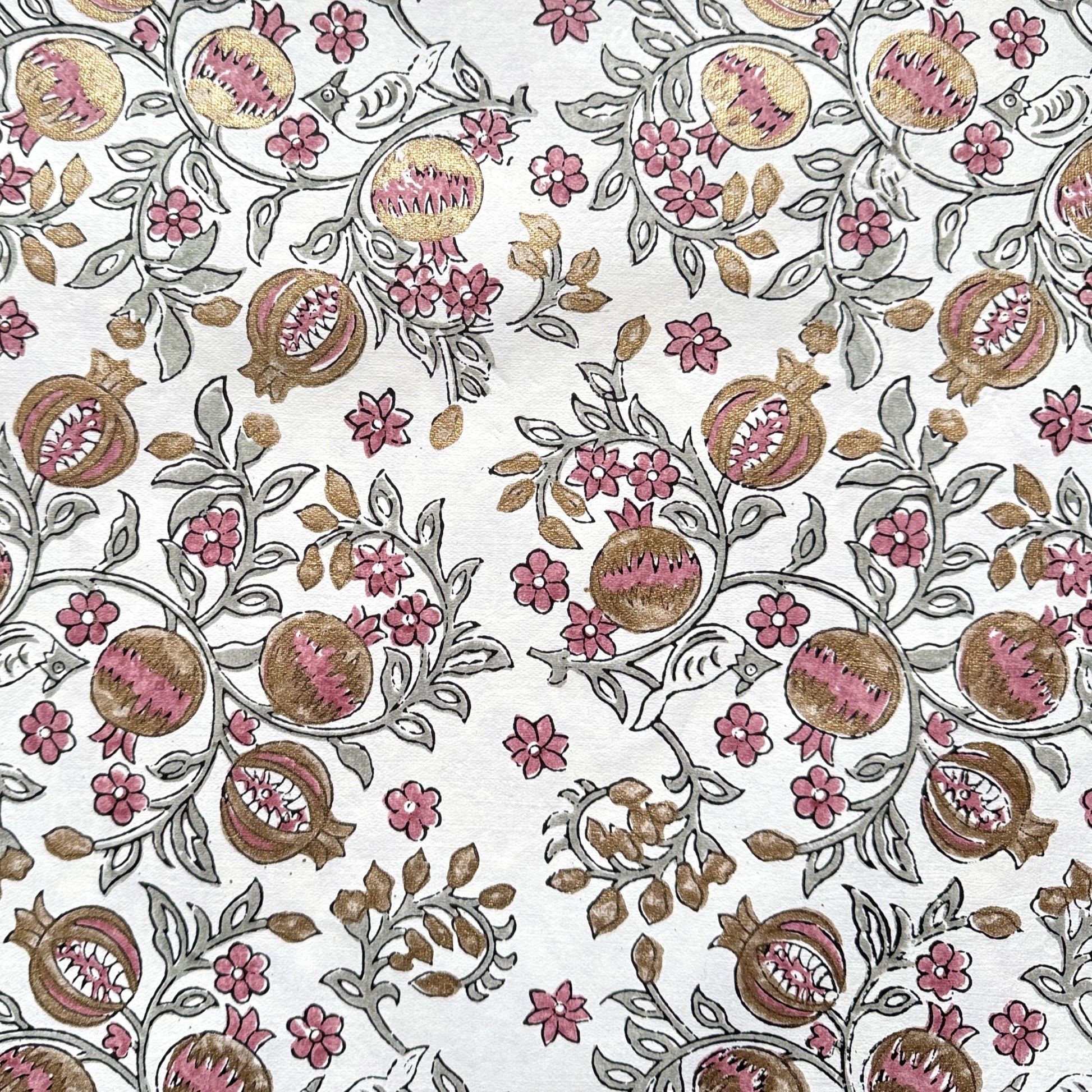 hand block printed wrapping paper by Paper Mirchi.  Repeat pattern of pomegranates in pink and green within a gold accent design.