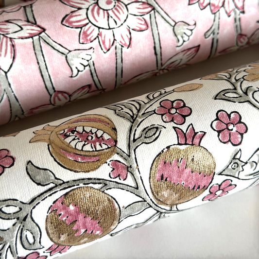 hand block printed wrapping paper by Paper Mirchi.  Repeat pattern of pomegranates in pink and green within a gold accent design. close up