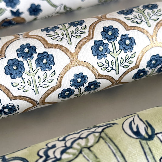 hand block printed wrapping paper with a small flower design in indigo and green surrounded by a gold trellis design. By Paper Mirchi. Close up