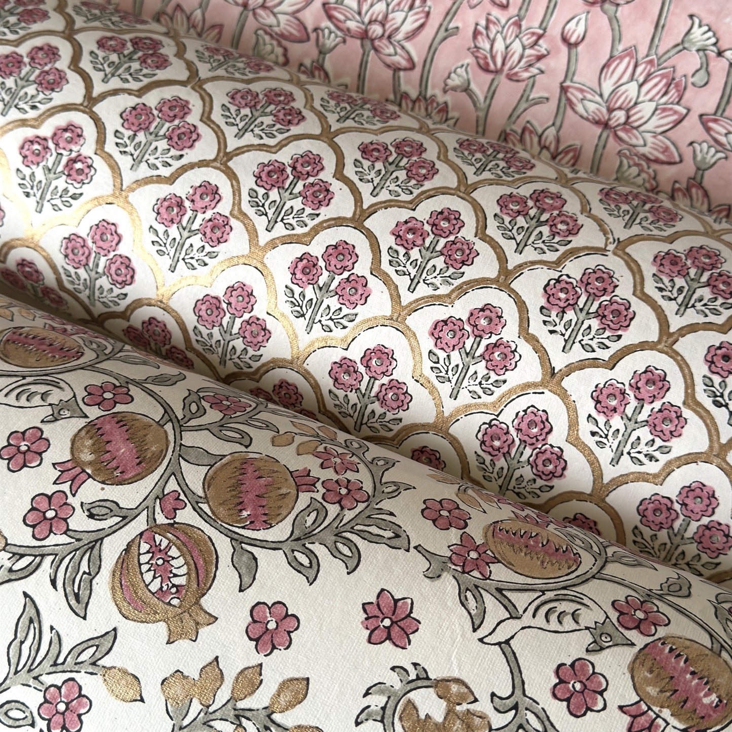 hand block printed wrapping paper by Paper Mirchi.  Repeat pattern of little flowers in pink and green within a gold trellis design. pictured with coordinating designs