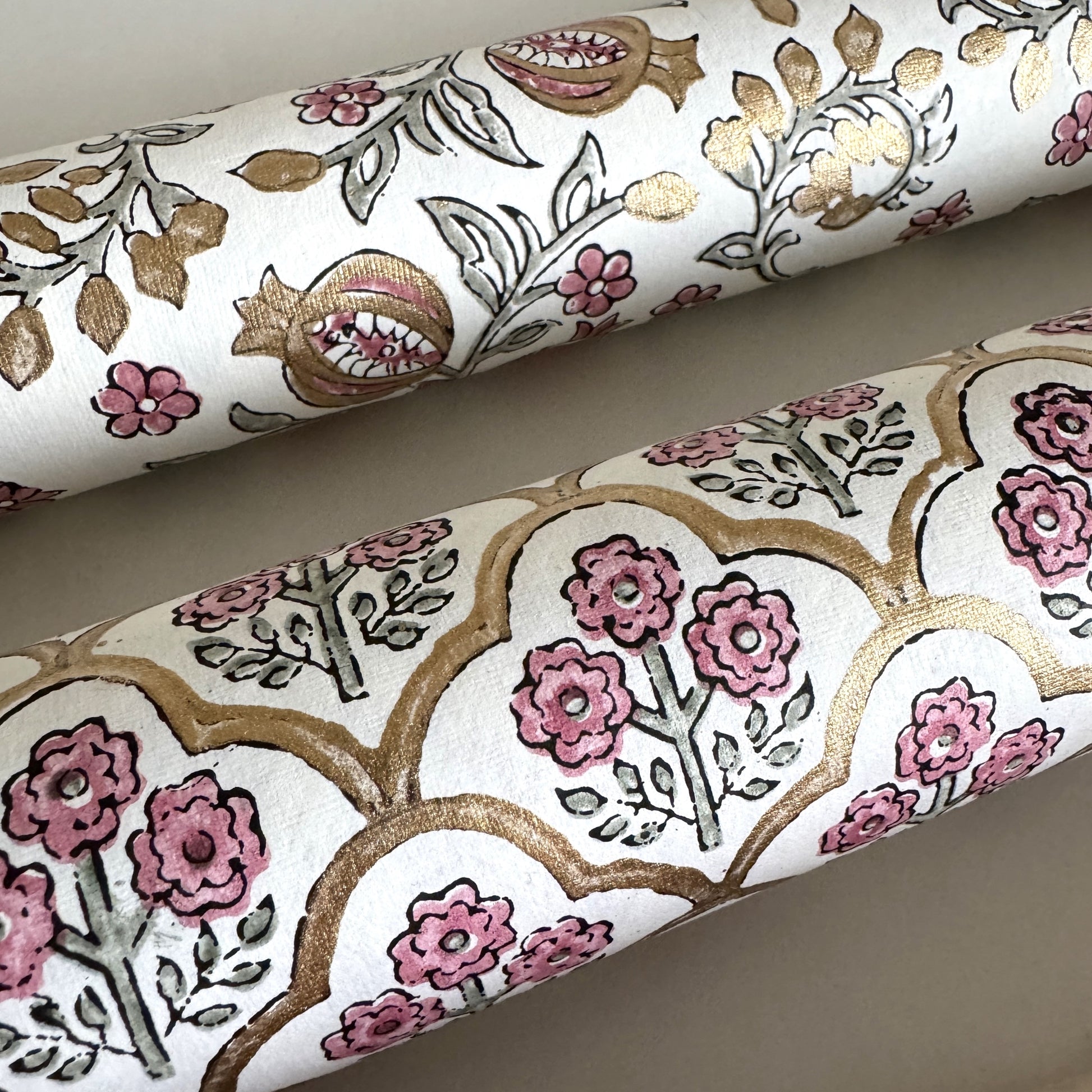 hand block printed wrapping paper by Paper Mirchi.  Repeat pattern of little flowers in pink and green within a gold trellis design. Close up