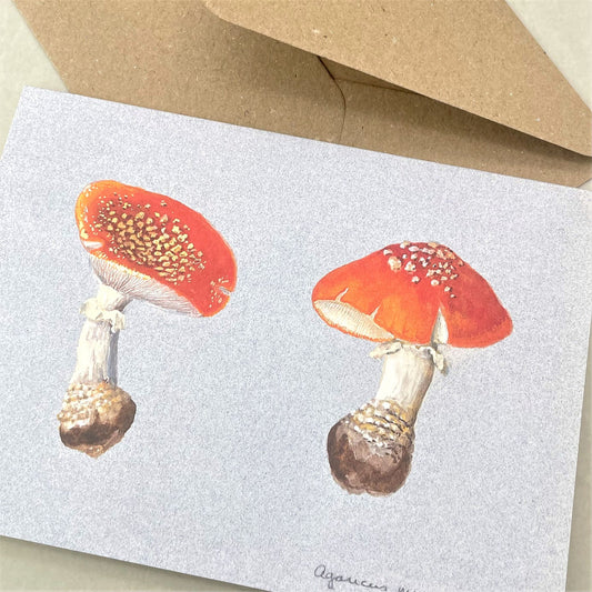 greetings card with image of two fly agaric toadstools, soft blue backdrop, by the pattern book