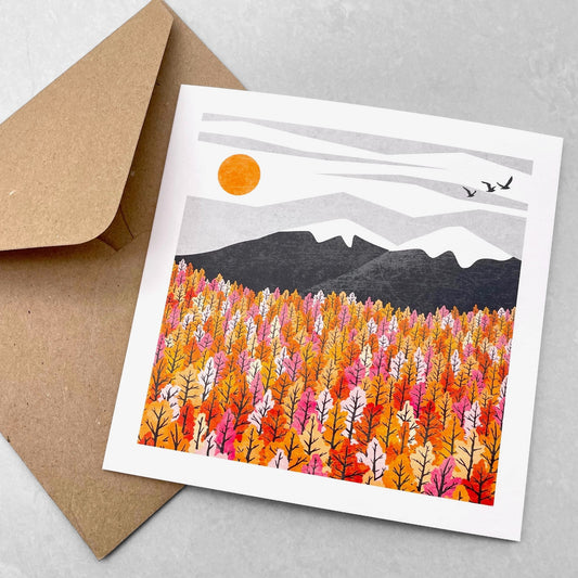 A greetings card by Ruth Thorp Studio of a landscape of trees and hills in autumnal colours, with envelope