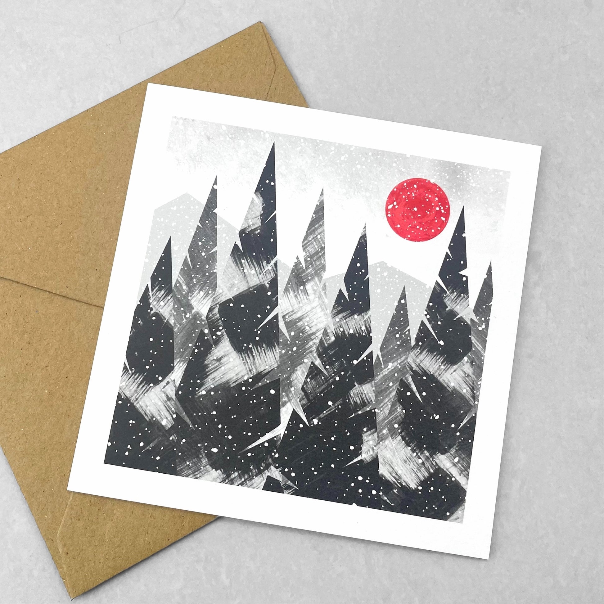 A pack of 4 cards with different designs inspired by snowfall, by Ruth Thorp Studio. Trees with a deep red sun in the snow