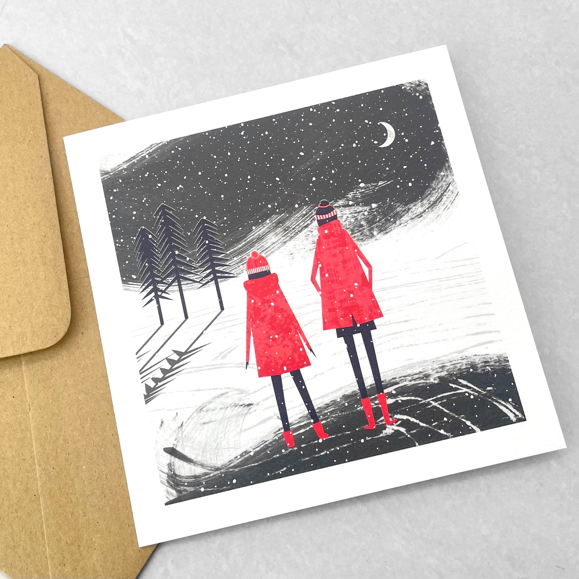 A pack of 4 cards with different designs inspired by snowfall, by Ruth Thorp Studio. Two children with red coats watching the snow
