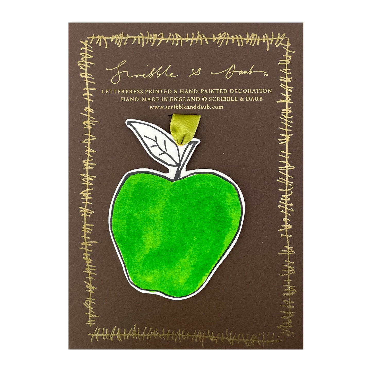 an apple shaped hanging ornament made of thick 1050gsm off-white card, letterpress printed in black and then hand painted in bright green ink. It has a chartreuse green satin ribbon to hang the ornament with. By Scribble & Daub. Pictured on a gold-foiled brown board.