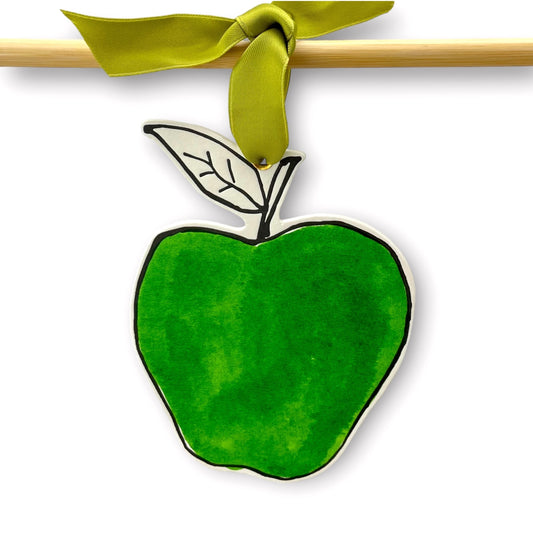 an apple shaped hanging ornament made of thick 1050gsm off-white card, letterpress printed in black and then hand painted in bright green ink. It has a chartreuse green satin ribbon to hang the ornament with. By Scribble & Daub