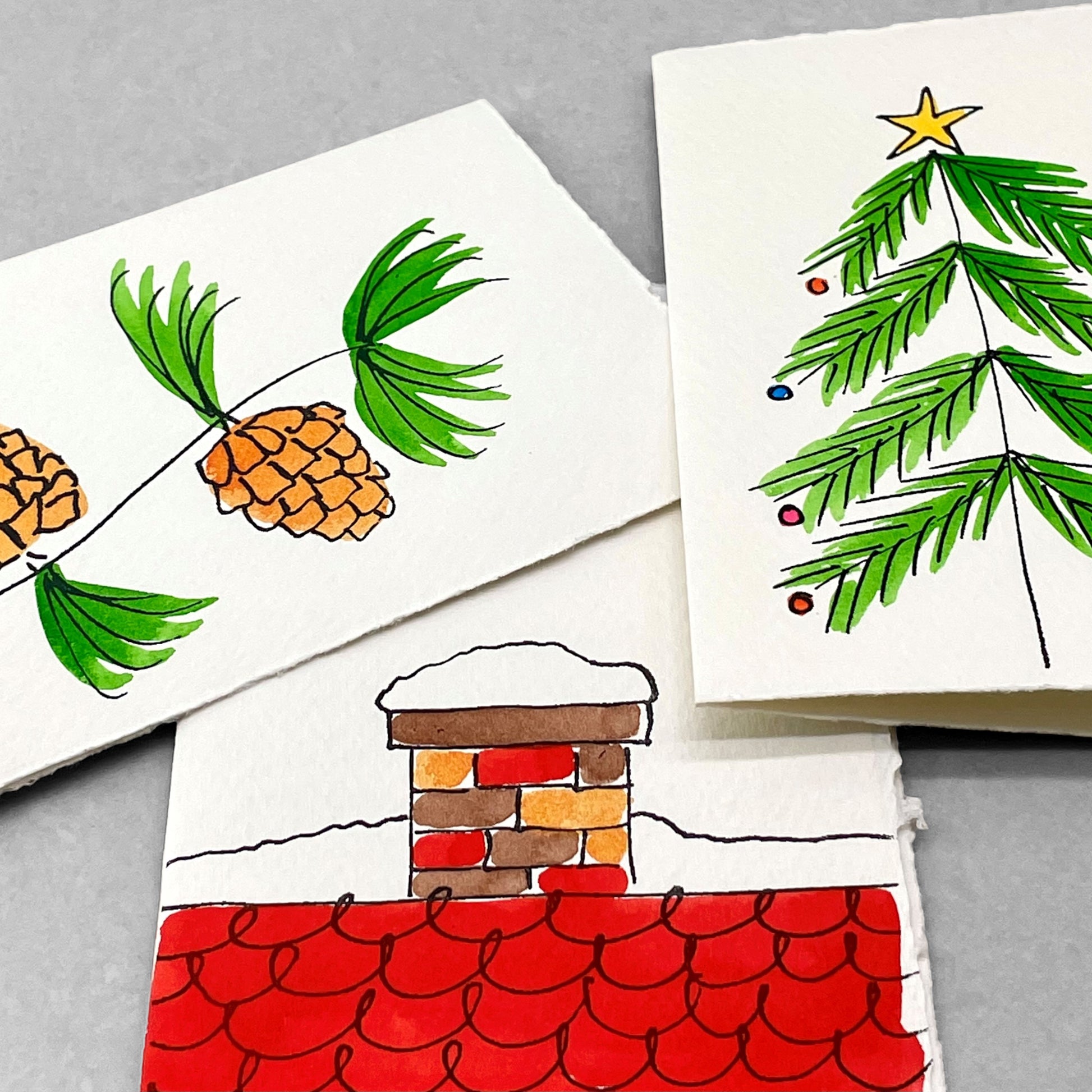 hand-painted greetings card of some pine cones, by Scribble and Daub, pictured with other card designs