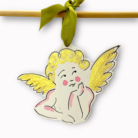 a cherub shaped hanging ornament made of thick 1050gsm off-white card, letterpress printed in black and then hand painted in pale pink and gold ink. It has a chartreuse green satin ribbon to hang the ornament with. By Scribble & Daub. 