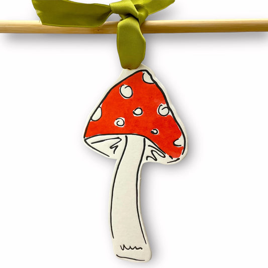 a mushroom shaped hanging ornament made of thick 1050gsm off-white card, letterpress printed in black and then hand painted in red ink. It has a chartreuse green satin ribbon to hang the ornament with. By Scribble & Daub. 