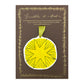 a star shaped hanging ornament made of thick 1050gsm off-white card, letterpress printed in black and then hand painted in yellow ink. It has a chartreuse green satin ribbon to hang the ornament with. By Scribble & Daub. Pictured on a gold-foiled brown board.