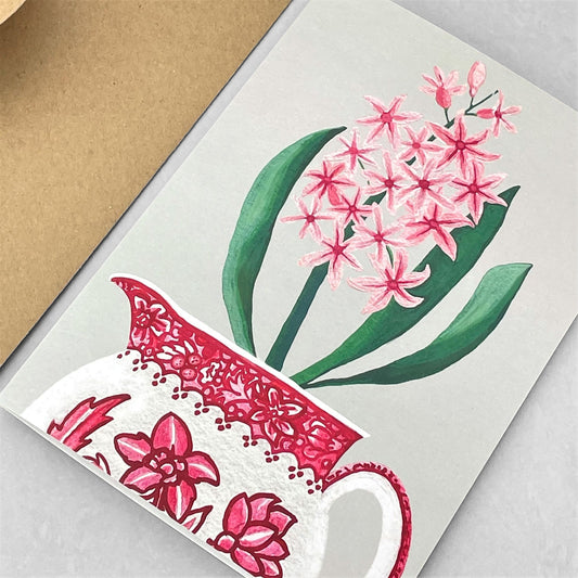 greeting card of a painting of a pink hyacinth in a red and cream jug with a hellebore flower design by Susie Hamilton
