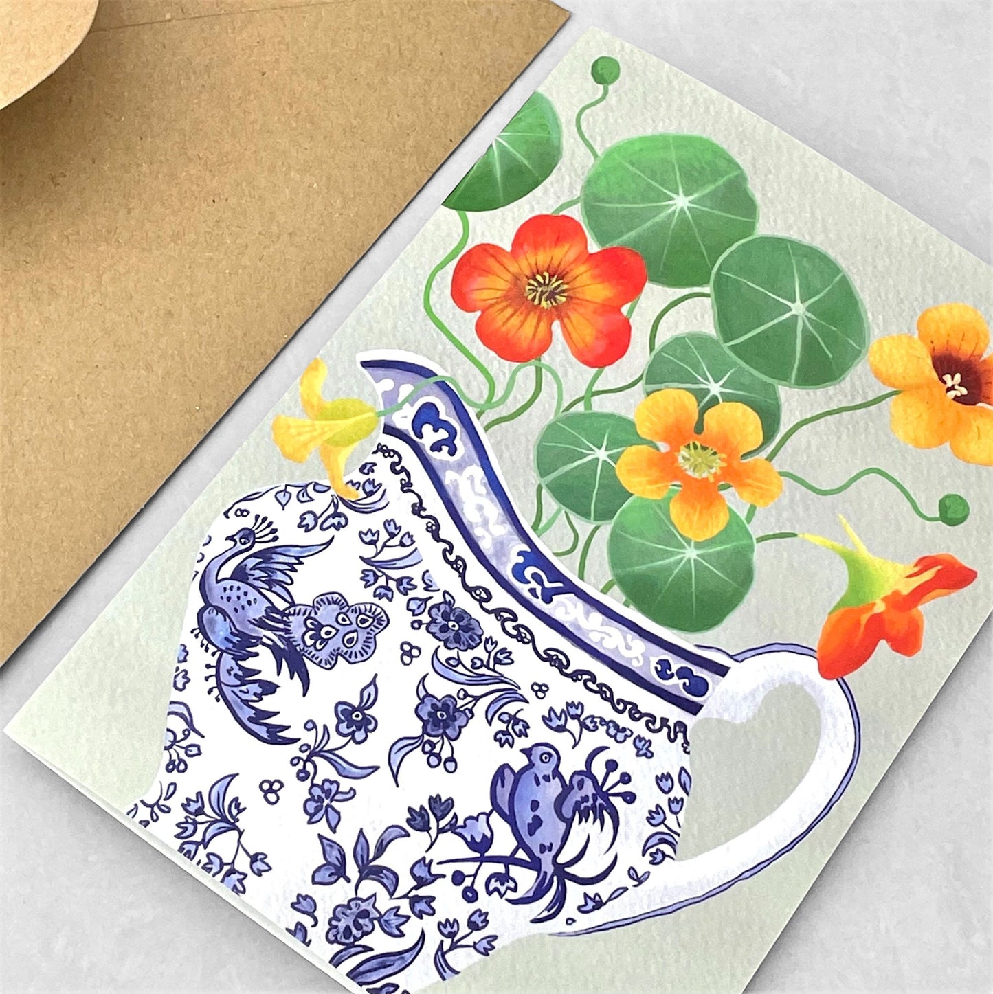 greeting card of a painting of yellow and orange nasturtiums in a blue and white jug with a bird design by Susie Hamilton