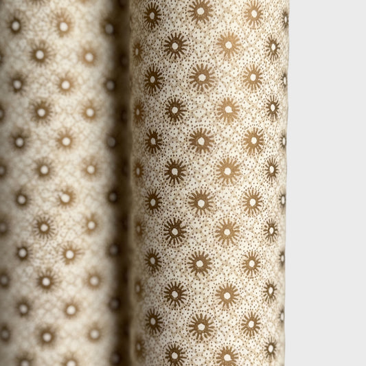 a sheet of italian wrapping paper with gold snowflakes on a cream backdrop. Close up