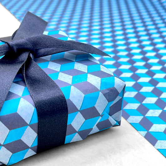 Italian patterned wrapping paper "Carta Varese" by Grafiche Tassotti. A pattern of blue, aqua a navy geometric cubes with a 3D effect. Close up