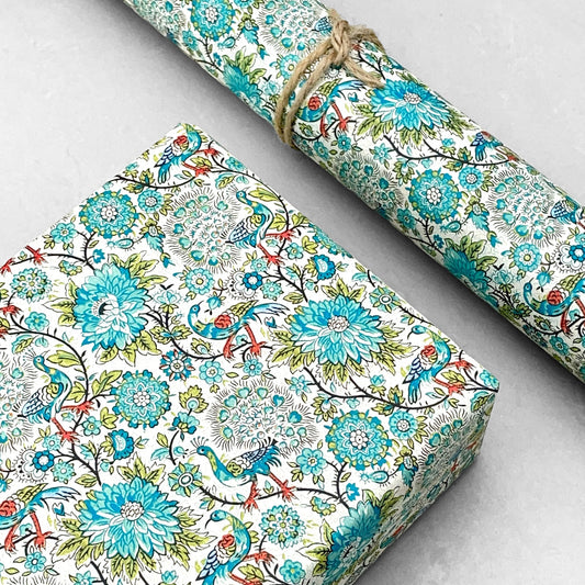italian patterned wrapping paper "Carta Varese" by Grafiche Tassotti. Pattern of peacocks, flowers and foliage in tones of blue, aqua, green and red.  Pictured as a present