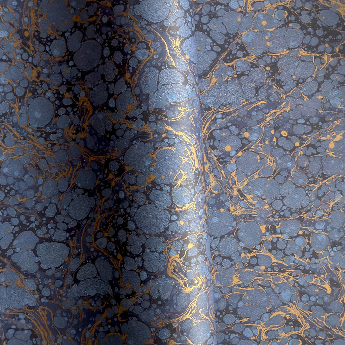 a sheet of Italian wrapping paper by Tassotti with a marbled pattern in dark and light blue with gold veins