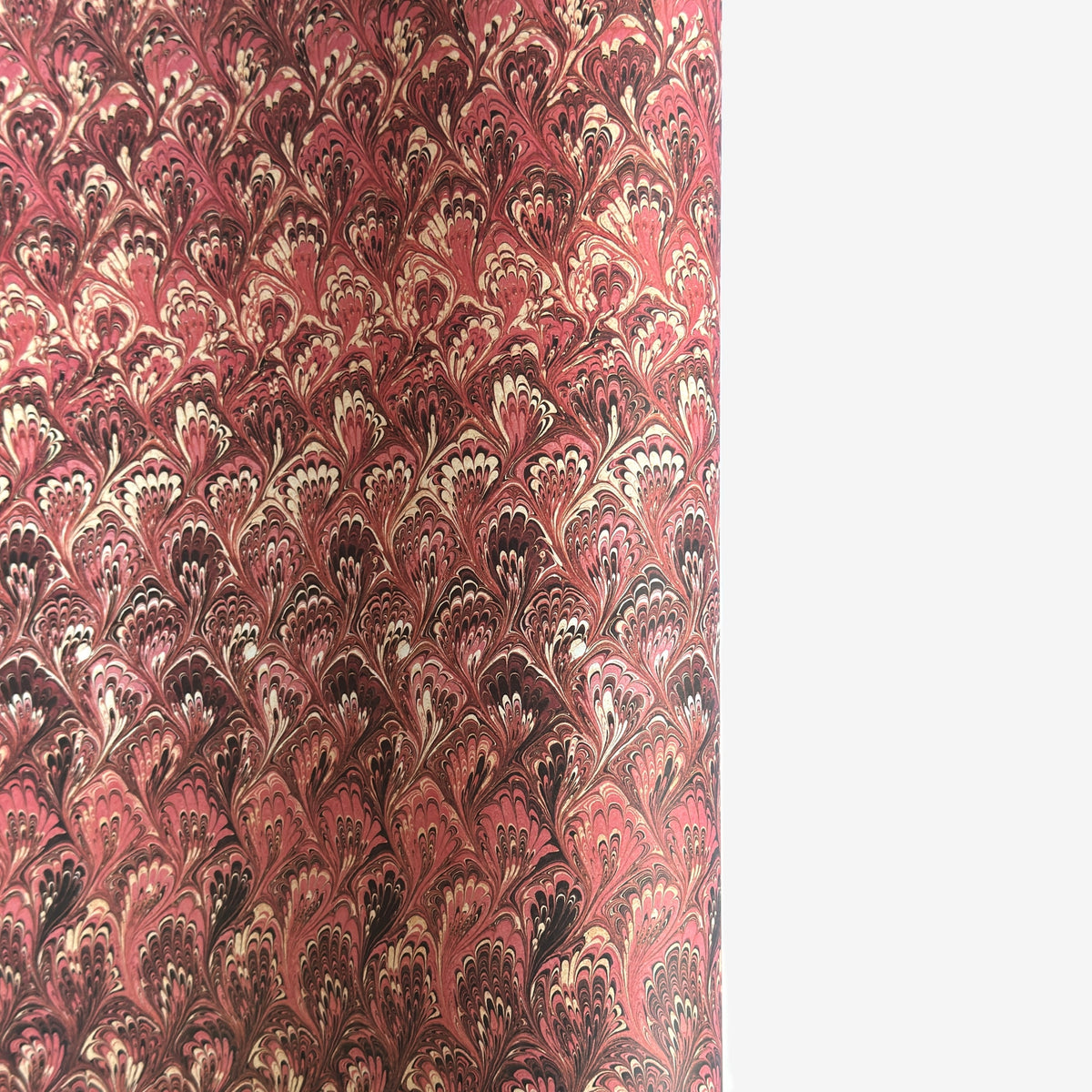 a sheet of Italian printed marbled paper with a marble design in pink, maroon and white