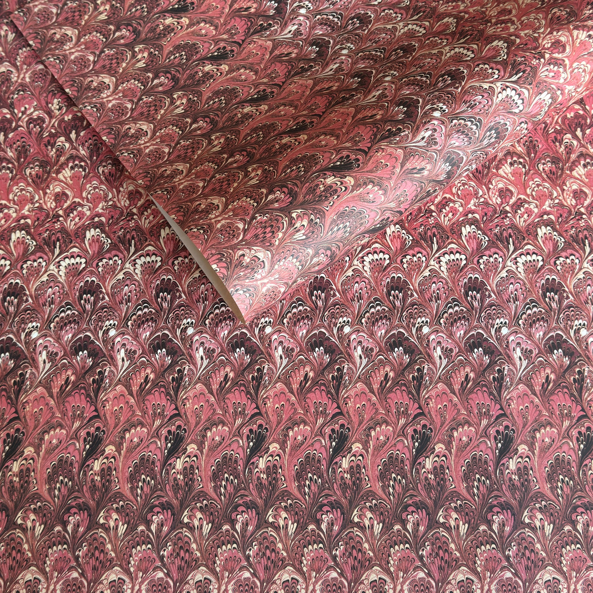 a sheet of Italian printed marbled paper with a marble design in pink, maroon and white