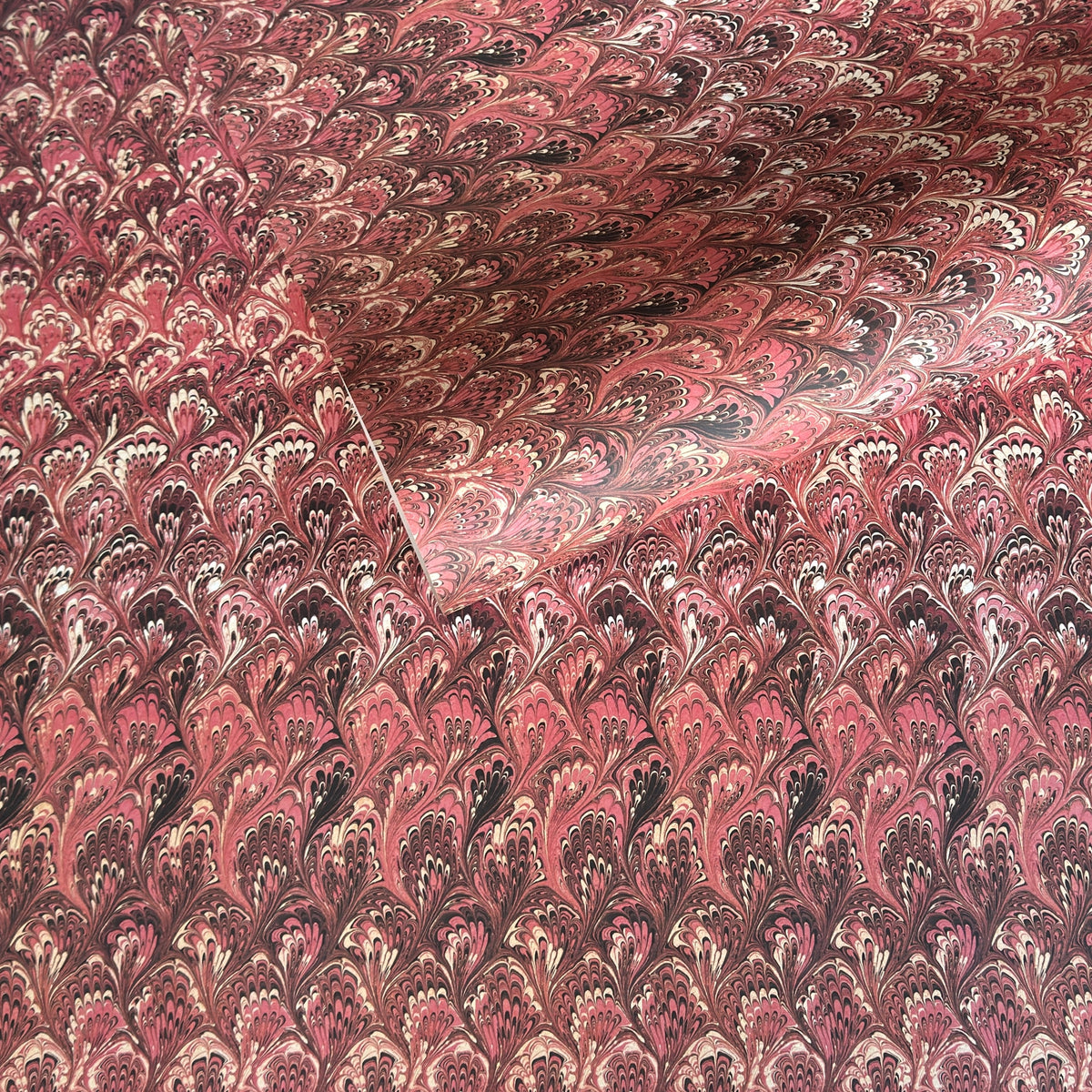 a sheet of Italian printed marbled paper with a marble design in pink, maroon and white